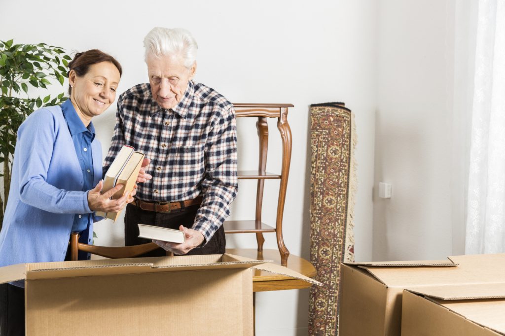 elderly couple packing up their books in cardboard boxes