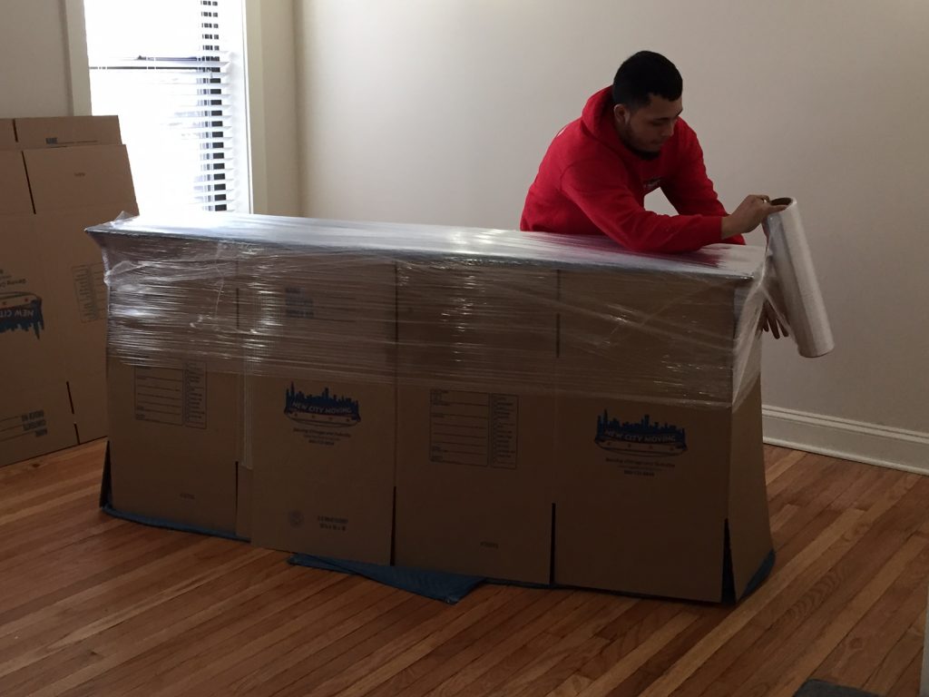 new city moving employee wrapping cardboard boxes with wrapping paper